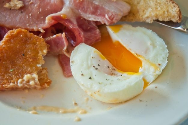 Desayuno inglés escalfados deliciosos huevos medio cocidos y tocino