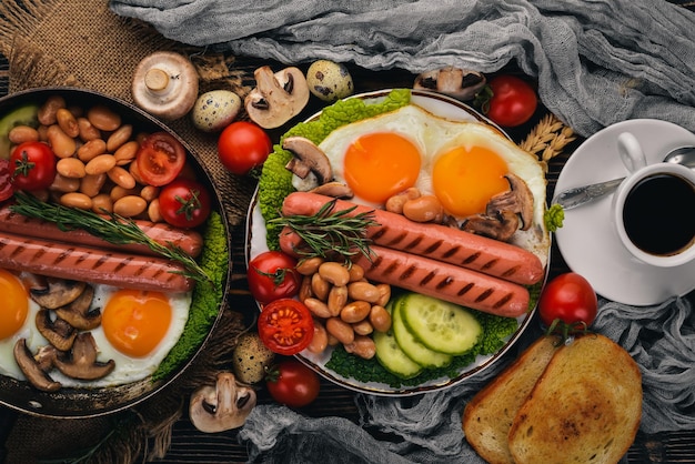 Desayuno inglés huevo frito frijoles tomates champiñones tocino y tostadas Vista superior sobre un fondo de madera