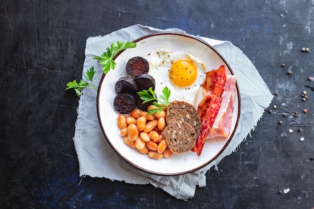 Desayuno inglés huevo frito morcilla morcilla pan de cereales frijoles tocino huevos revueltos