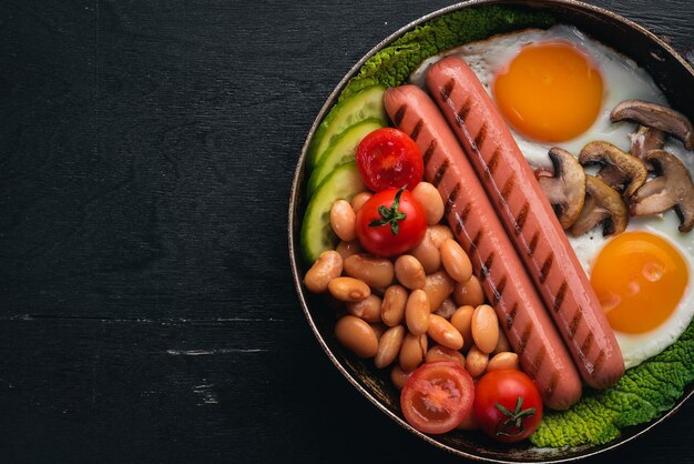 Desayuno inglés Huevos fritos salchichas tocino frijoles tostadas tomates taza de café en la mesa de piedra Vista superior con espacio para el texto