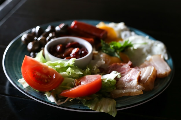 Desayuno inglés con huevos fritos, salchichas, tocino, frijoles.