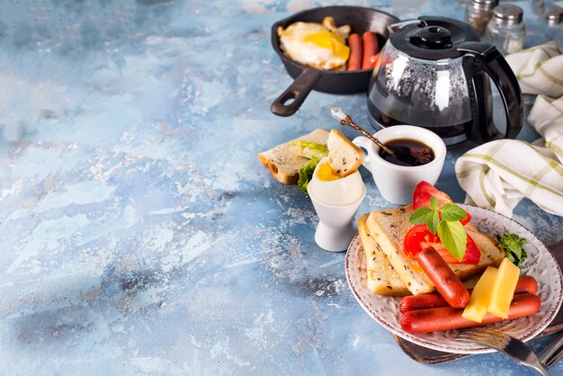 Foto desayuno inglés. huevos fritos, salchichas, tostadas, tomates en mesa de piedra.