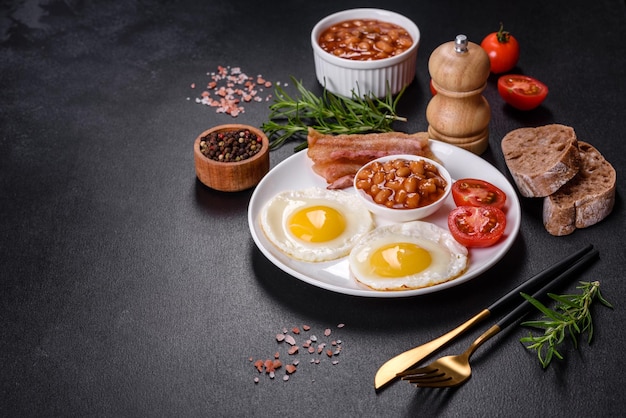 Desayuno inglés con huevos fritos tocino frijoles tomates especias y hierbas