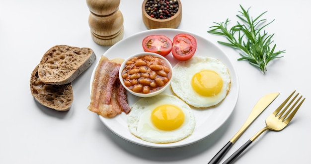 Desayuno inglés con huevos fritos tocino frijoles tomates especias y hierbas