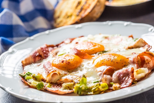 Desayuno inglés tocino frito con jamón y eggson plato blanco.