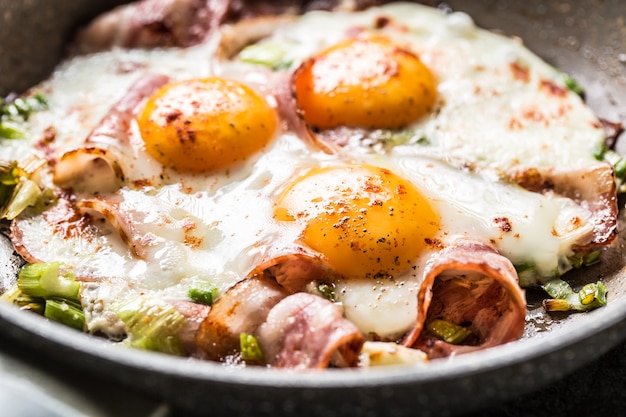 Desayuno inglés tocino frito con jamón y huevos en cacerola de cerámica.