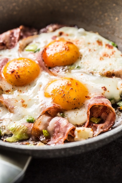 Desayuno inglés tocino frito con jamón y huevos en cacerola de cerámica.