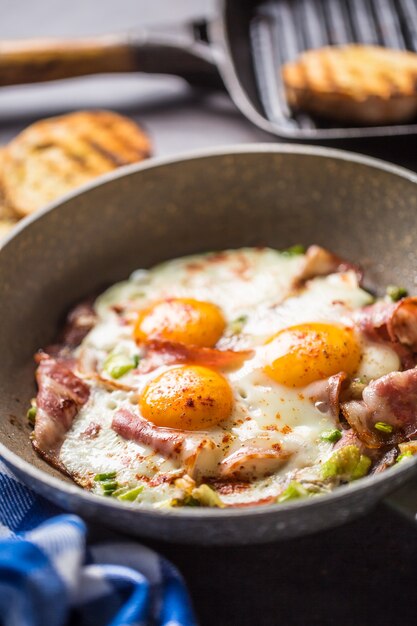 Desayuno inglés tocino frito con jamón y huevos en cacerola de cerámica.