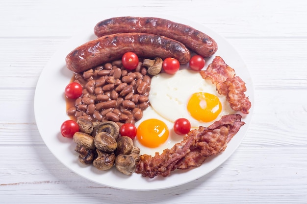 Desayuno inglés con tocino, salchichas, huevos, tomates, setas y frijoles.