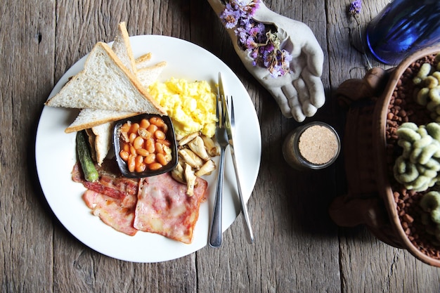 Desayuno con jamón, huevo frito y pan sobre fondo de madera low key