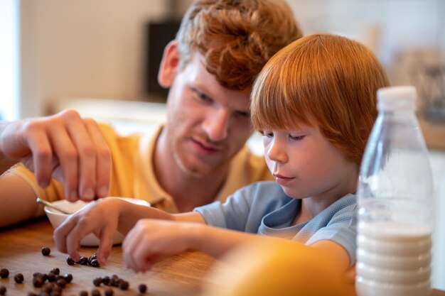 Desayuno juntos. Papá e hijo sentados a la mesa y desayunando