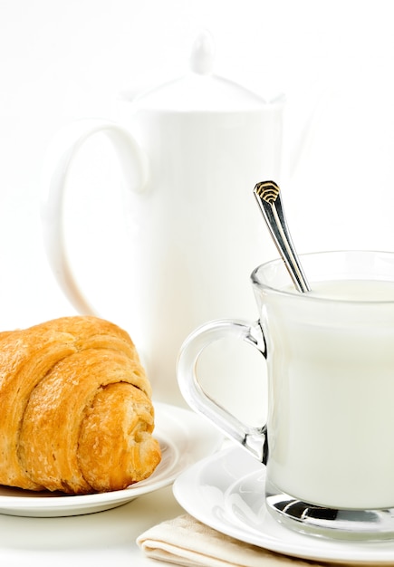 Desayuno, leche en una taza con un croissant