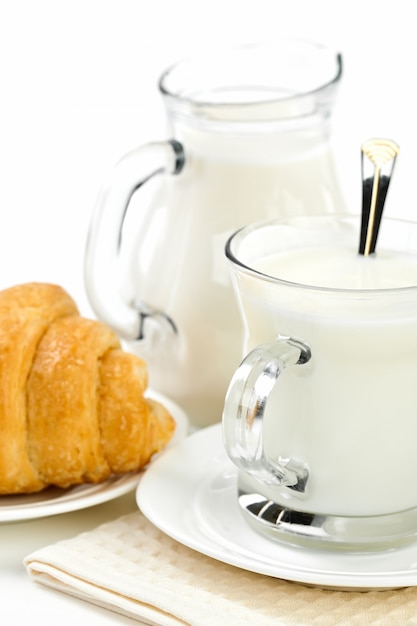 Desayuno, leche en una taza con un croissant