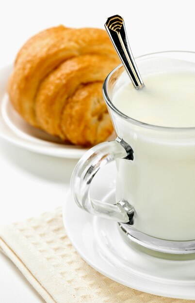 Desayuno, leche en una taza con un croissant