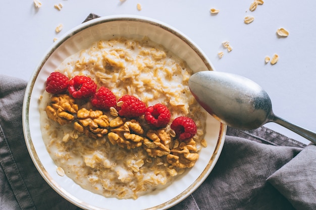 Foto desayuno de la mañana, avena en leche con frambuesas y nueces, vista superior