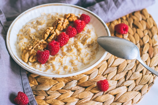 Foto desayuno de la mañana, avena en leche con frambuesas y nueces