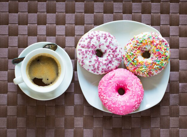 Desayuno por la mañana con donas de colores y café.