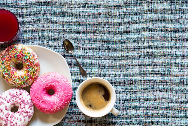 Desayuno por la mañana con donas de colores y café.