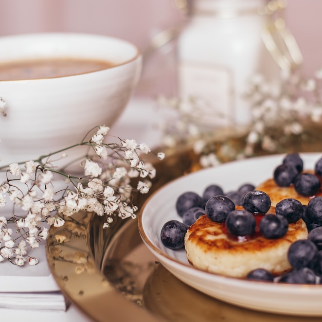 Desayuno matutino, café y tartas de queso con arándanos.