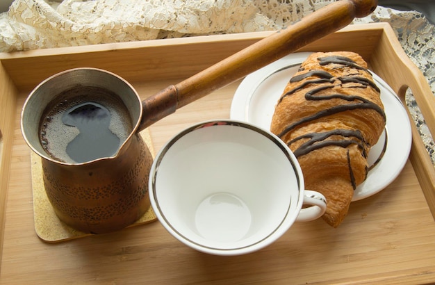 Desayuno matutino en la cama una taza de café con croissant en bandeja de madera