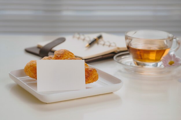 Desayuno matutino en la sala de estar con croissant francés, taza de té, bolígrafo y cuaderno sobre la mesa de piedra