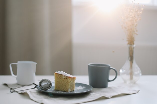 Desayuno matutino con un trozo de jarra de tarta casera fresca y una taza de café sobre una mesa