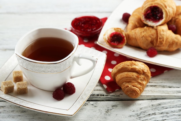 Desayuno con mermelada de té y croissants recién hechos sobre fondo de madera