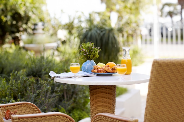 Desayuno en la mesa de hojaldre fresco, cruasanes, frutas y zumo de naranja recién exprimido