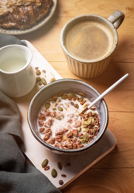 Desayuno en una mesa de madera: granola, croissant, café y leche.