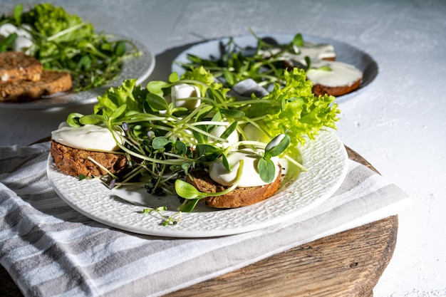 Desayuno con microgreen en un plato Pan tostado salsa de crema de queso mozzarella Comida con brotes verdes de micro green Dieta saludable Comida sencilla Ensalada con brotes de girasol rúcula rábano mostaza