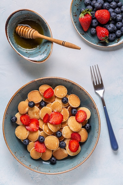 Desayuno de moda con mini panqueques, arándanos y fresas, vista superior.