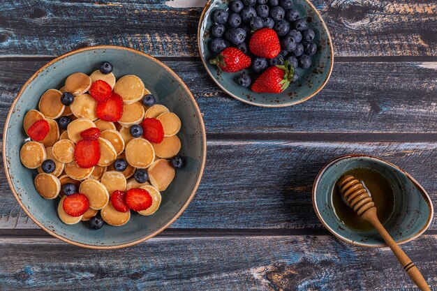 Desayuno de moda con mini panqueques, arándanos y fresas, vista superior.