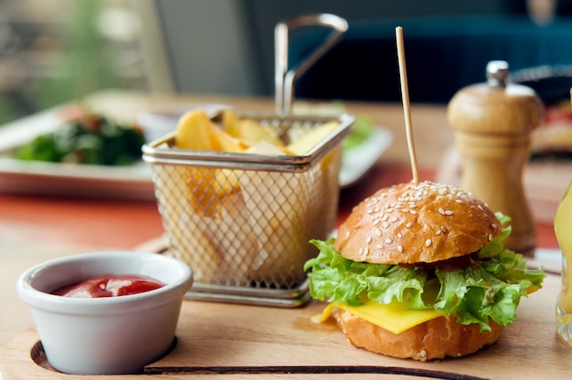 Desayuno para niños con mini hamburguesa, jugo, pastel y papa