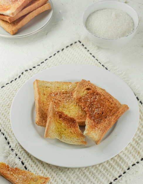 Desayuno con pan tostado espolvoreado con azúcar servido en un plato blanco