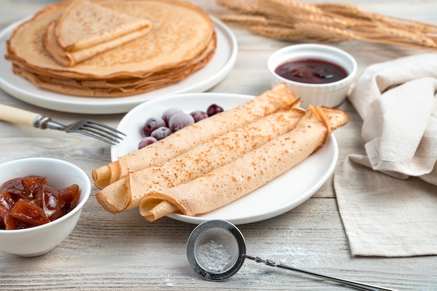 Desayuno con panqueques y bayas congeladas en una mesa de madera clara. Vista lateral. Concepto de superficie culinaria