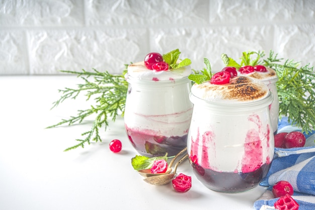 Desayuno de postre con capas de arándanos en frascos pequeños para la mañana de Navidad. Postre casero de merengue de arándanos al horno, con arándanos frescos y menta