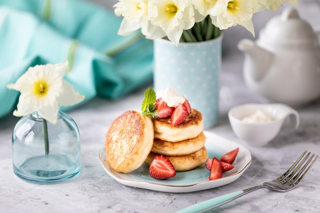 Desayuno de primavera con flores, tartas de queso y bayas frescas