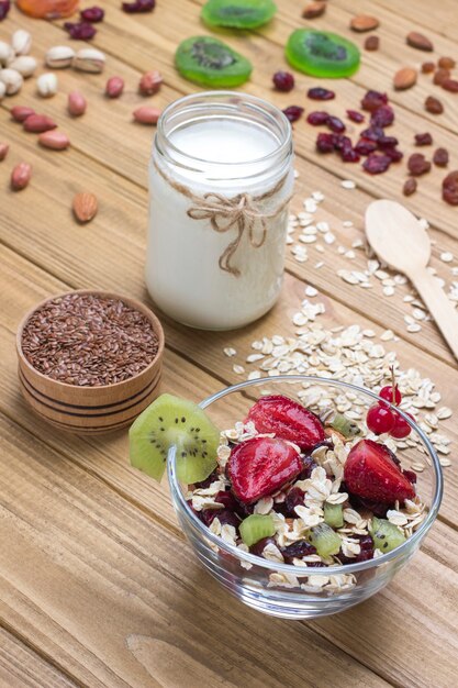 Desayuno proteico equilibrado con muesli. Frutas, semillas de bayas, nueces. Yogur de coco. Comida vegetariana de dieta saludable. Vista superior Superficie de madera. Copia espacio