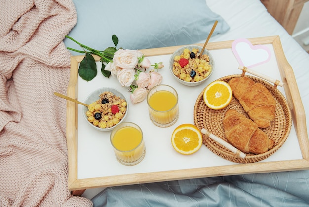 Desayuno romántico con café, gofres, jugo de naranja y rosas.