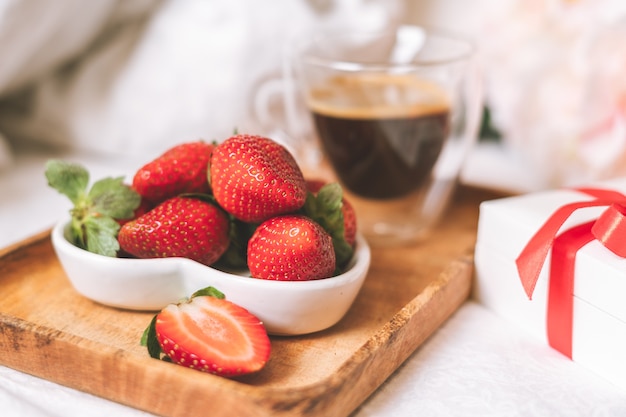 Desayuno romántico en la cama con fresas y café.