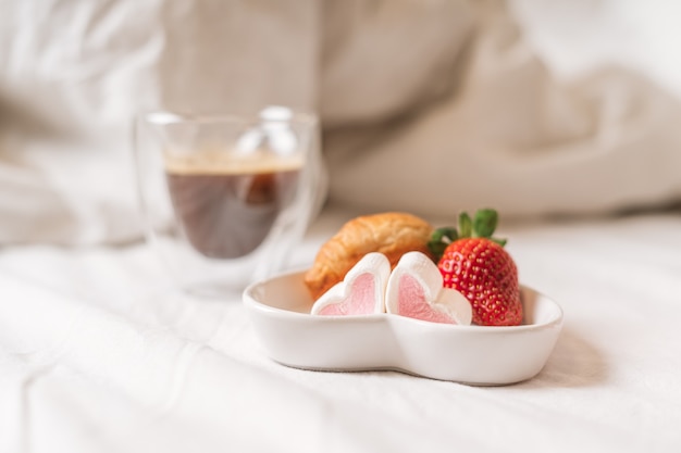 Desayuno romántico en la cama con fresas y café.