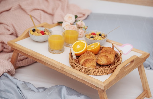 Desayuno romántico con croissants, jugo de naranja y rosas