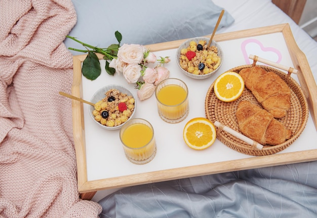 Desayuno romántico con croissants, jugo de naranja y rosas
