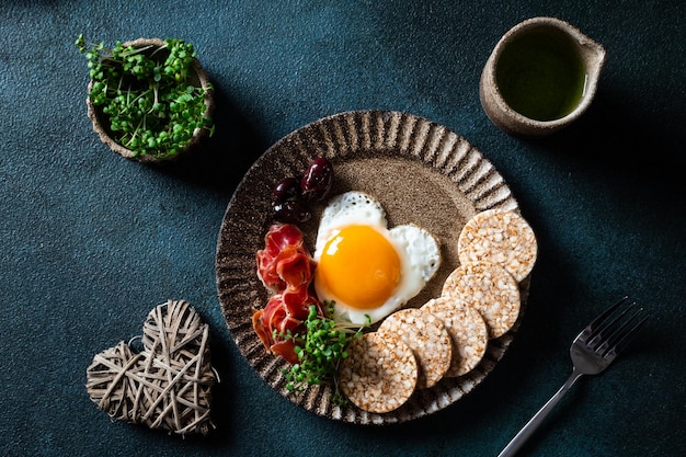 Desayuno romántico huevos fritos en forma de corazón y aceitunas Desayuno saludable Tortas de arroz con huevos y hamón Desayuno dietético cetogénico Vista superior