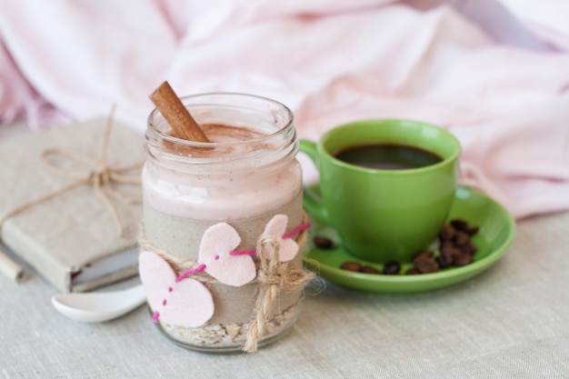 Desayuno romántico y rico: avena con yogur de bayas y canela, café negro y un cuaderno para discos vintage