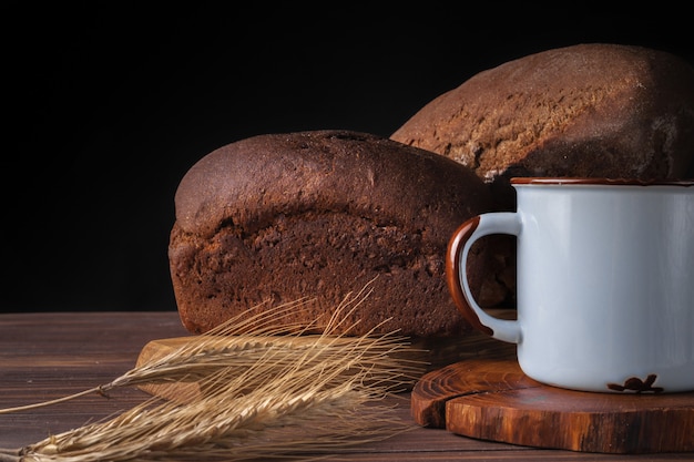 Desayuno rústico con pan y una taza de leche en una mesa de madera.