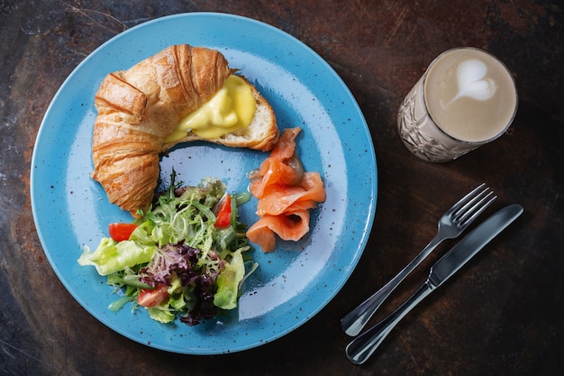 Desayuno sabroso Croissant con queso y salmón y café.