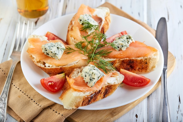 Desayuno sabroso Sandwiches con salmón y queso y tomates cherry en un blanco de madera