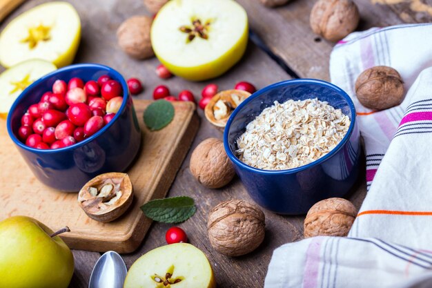 Desayuno saludable - avena, arándanos, nueces, manzanas en una mesa de madera