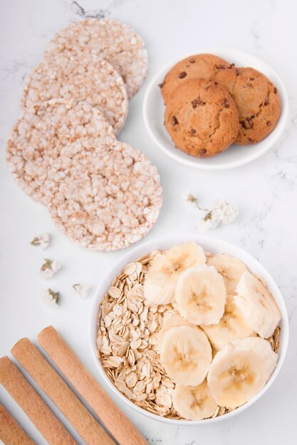 Desayuno saludable de avena con plátano y galletas de avena sobre un fondo blanco.